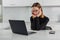 Girl in glasses sadly looks at the laptop monitor, sits at home in the kitchen