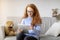 Girl in glasses using digital tablet, sitting on couch