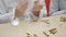 Girl glues wooden parts sitting at table in room.