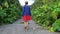 Girl goes along abandoned road overgrown by hogweed