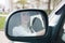 The girl goes behind the wheel of a car and looks in the side mirror. Woman driving