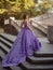Girl in gorgeous purple long dress standing on the stairs