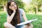 Girl on grass on the blanket feeling tired while trying and bored read book to relax outside with books