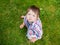Girl on the grass looks up. looks at the camera from below. wants into small hands. Playful little boy looking up. baby