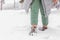 A girl in green pants walks through the snow in winter.