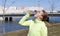 Girl in green sports top drinking water from a bottle on the background of the canal buildings, athlete