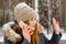 Girl greets someone by hand, talking on the phone in the winter in the open air