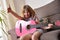 Girl with guitar raising hand success gesture at home