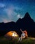 Girl and guy looking at the shines starry sky at night. Couple sitting near camping