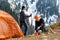 Girl and a guy at a stop with a tourist tent drinking tea or coffee on a background of forest snow-capped mountains. A walking met