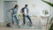 Girl and guy vacuuming carpet in bedroom laughing having fun during clean-up