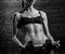 Girl gym dumbbells. Fitness model doing intense training. Woman working out with dumbbells on dark wooden background