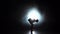 Girl gymnast with mace in hand revolve around him. Black background. Light rear. Silhouette. Slow motion