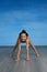 Girl gymnast smiles and shows a gymnastic exercise on the floor on a blue background.