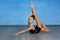 Girl gymnast smiles and shows a gymnastic exercise on the floor on a blue background.