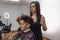 The girl hairdresser carefully makes a hairstyle for her client