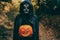 Girl with halloween make up, holding a pumpkin into the wood - Autumn holidays party concept concept - Focus on face