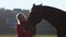 Girl with a hand feeds a horse and holds it for a reason . Slow motion