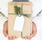 Girl hand holding craft and handmade christmas present gift boxes with tag.