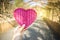 Girl hand holding pink wooden heart over blurred bamboo dome background