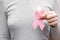 Girl hands holding pink breast cancer awareness ribbon on gray background. Concept healthcare and medicine beauty