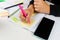 Girl Hands With Mobile Phone With Calendar Writing And List Of Work In Diary On Desk