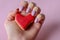 Girl hands with purple color nails polish holiding red heart cookie