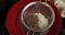 A girl hands sifting cocoa powder into bowl with flour on table. Top view