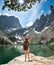 Girl with hands up standing on the rock on hiking trip in mountains.