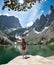 Girl with hands up standing on the rock on hiking trip in mountains.