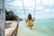 Girl hangig on beach swings on tropical island