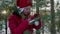 Girl hanging xmas ball on pine tree in winter forest