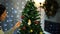 Girl hangs an angel figurine on a Christmas tree with colorful balls