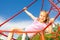 Girl hangs on red net ropes with two arms