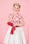 A Girl happiness blonde with red long gloves on pastel pink background. Pretty curls woman with pin-up make-up isolated in studio.