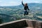 Girl happy jump. Motorcycle outfit. body protection turtle and knee pads on the edge of the top of the mountain. incredible view.