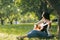 A girl in harmony with herself plays the guitar in the park. Hobbies, music, musician