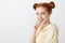 Girl has interesting plans on us. Portrait of curious attractive european woman with red hair and buns hairstyle biting