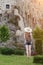 Girl in a hat with a backpack standing near the fortress. Back view