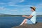 Girl in a hat catches fish on the river sitting on the pier