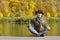 Girl in a hat and coat sitting on the pier. Autumn sunny day.