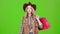Girl in a hat and cowboy boots comes with bags in her hands. Green screen