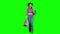 Girl in a hat and cowboy boots comes with bags in her hands. Green screen