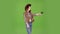 Girl in a hat, cowboy boots and a vest shoots a revolver. Green screen