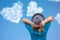 Girl in hat looks at clouds in heart shape soar in blue sky. Concept of love, romance and happy relations. Valentine day or