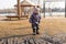 girl in a hat and overalls is standing in front of a large dirty puddle. spring walk