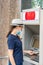 A girl in a hat and a protective medical mask withdraws cash from an ATM during quarantine