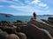 Girl in hat sitting on Acapulco bay rocks