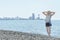 Girl in a hat stand along the seashore. City in the distance. Ba