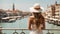 A girl in a hat and sundress summer traveler back to the camera romantic of Venice